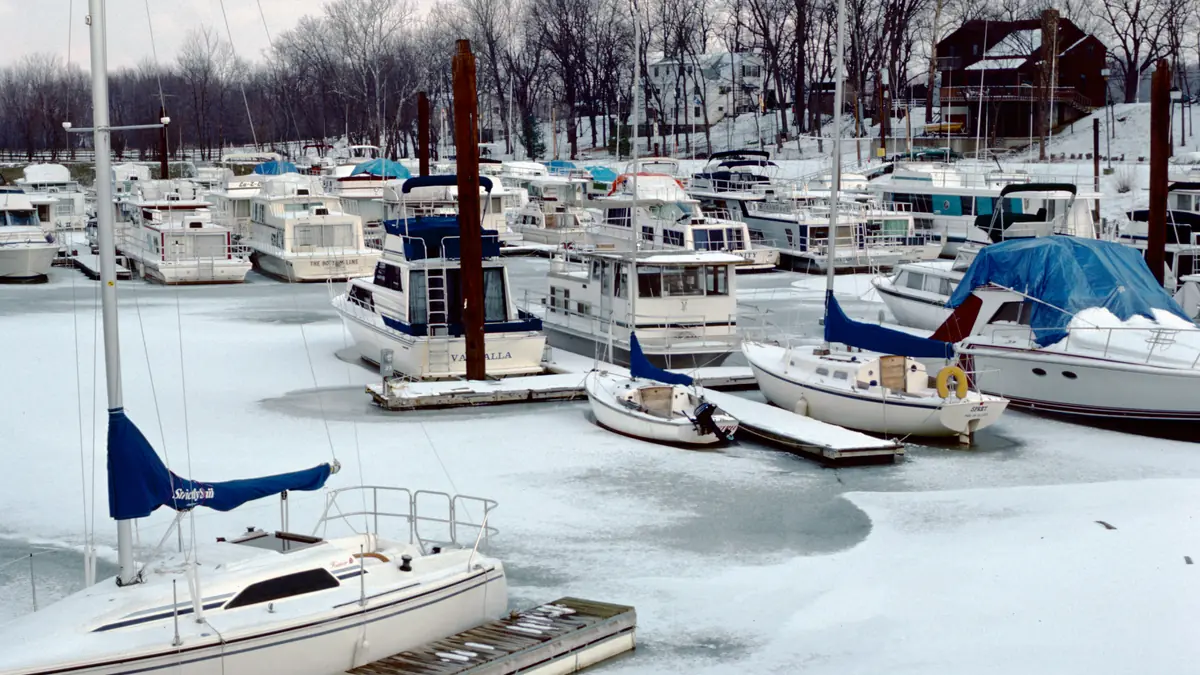Cruisers and sailboats docked at a marina in winter